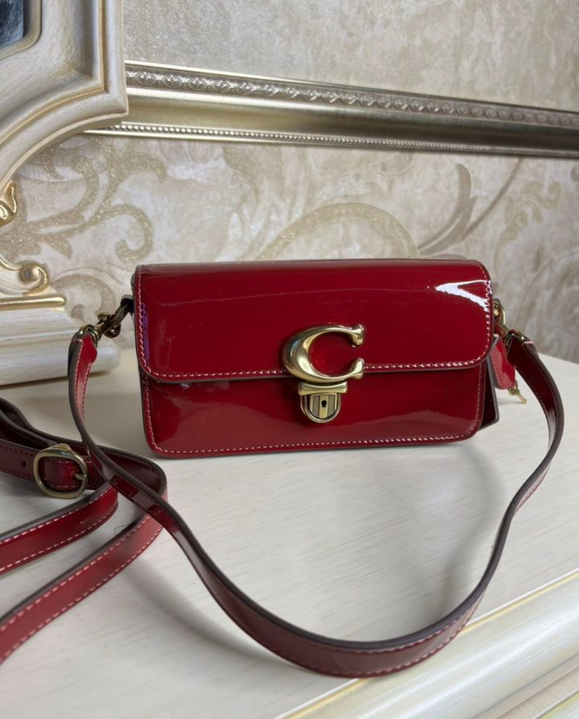 Heritage Compact Shoulder Bag in Glossy Crimson with Sculpted Gold Emblem